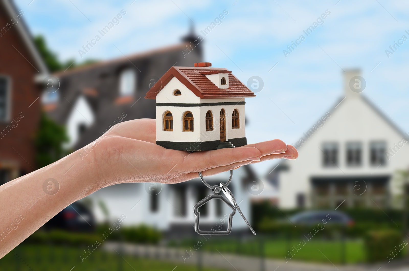 Image of Real estate agent holding house model and key against future dwelling, closeup