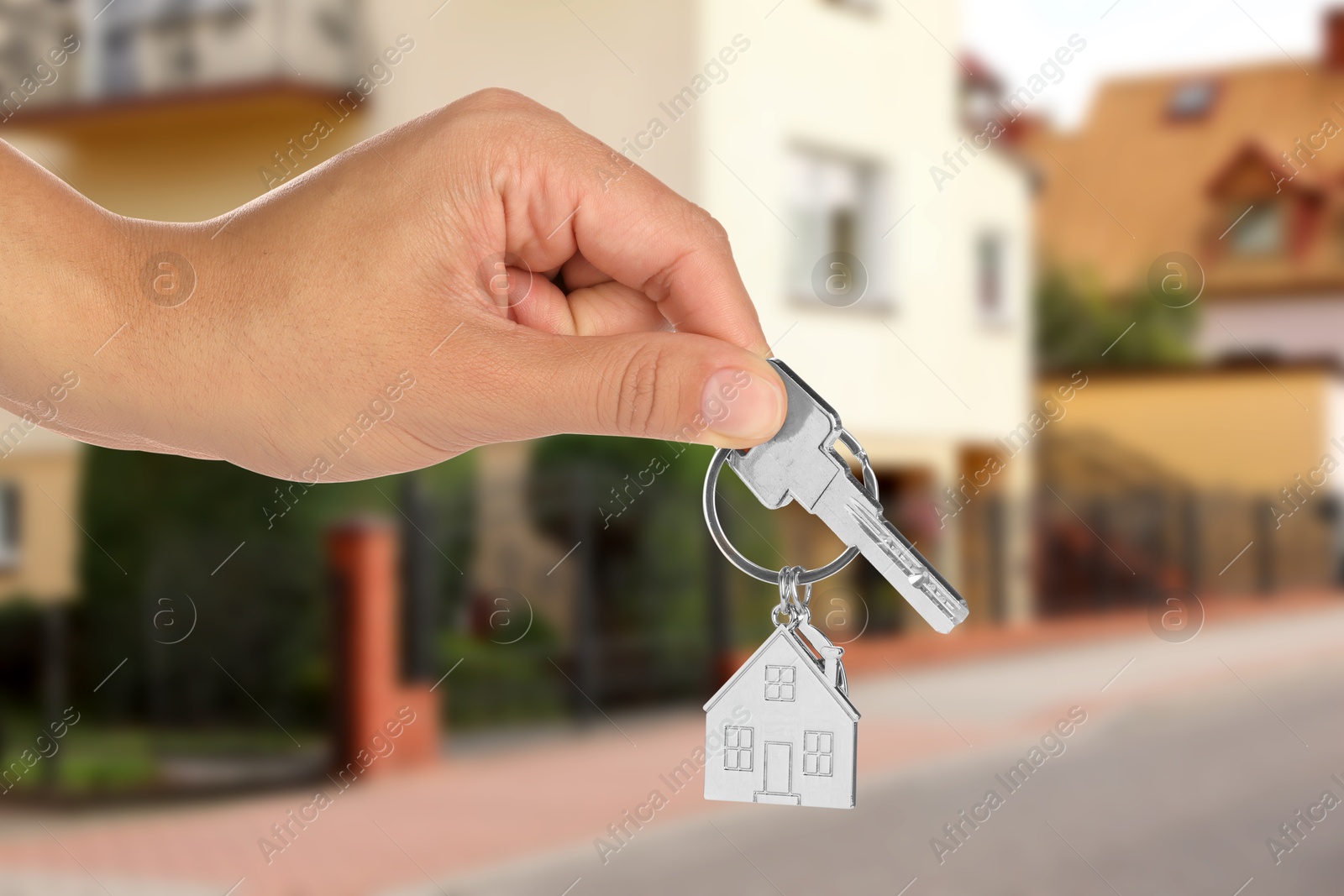 Image of Real estate agent holding house key against future dwelling, closeup