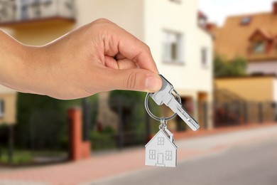 Image of Real estate agent holding house key against future dwelling, closeup