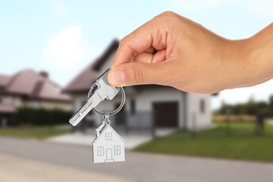 Real estate agent holding house key against future dwelling, closeup