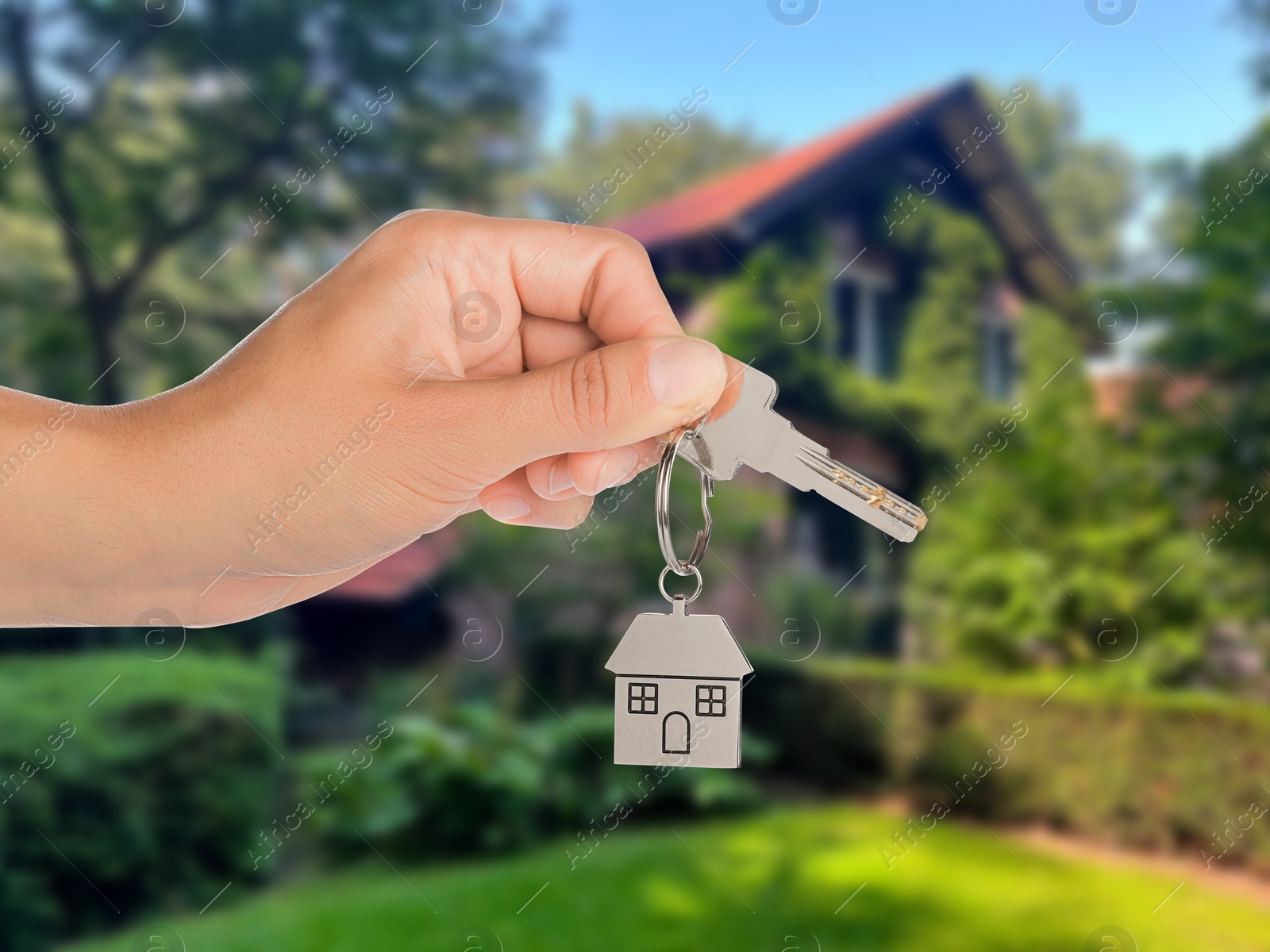 Image of Real estate agent holding house key against future dwelling, closeup