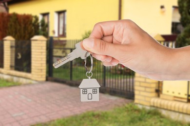 Image of Real estate agent holding house key against future dwelling, closeup