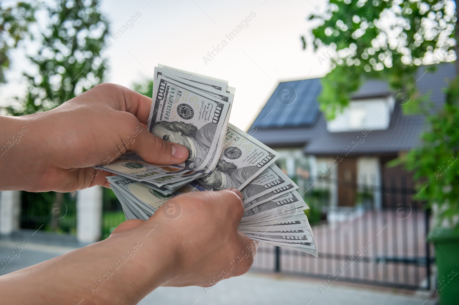 Image of Man counting money against beautiful house, closeup. Real estate purchase