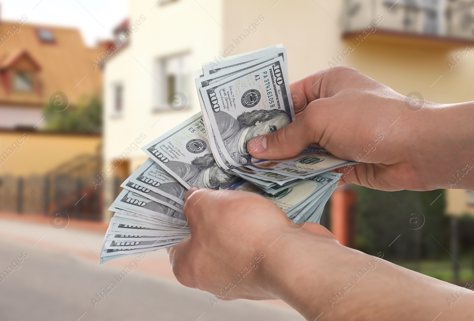 Image of Man counting money against beautiful house, closeup. Real estate purchase