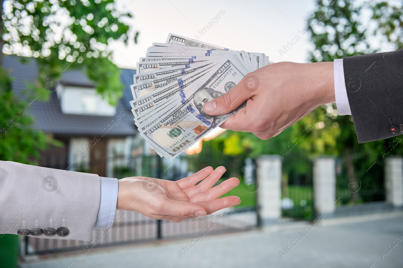 Image of Client giving money to real estate agent against beautiful house, closeup