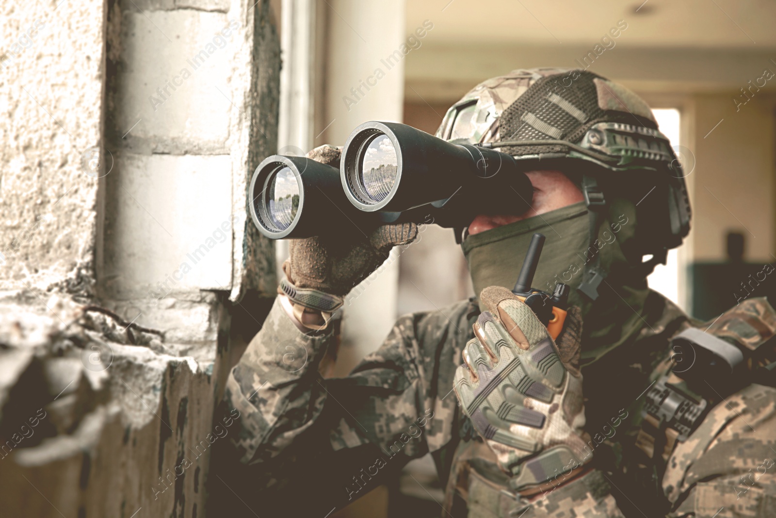 Image of Soldier using radio and binoculars in building during military operation