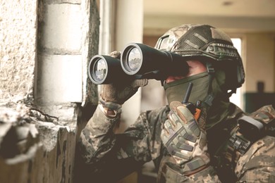 Image of Soldier using radio and binoculars in building during military operation