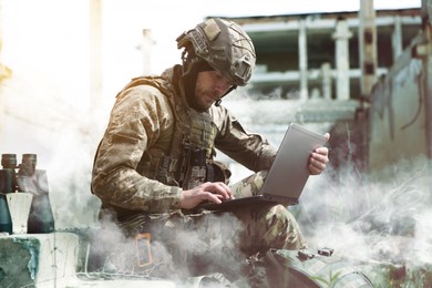 Image of Soldier using laptop near building during military operation