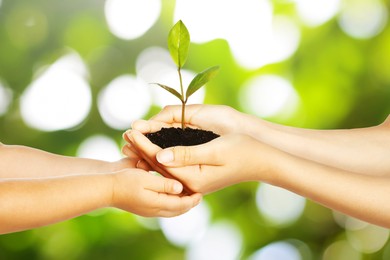 Image of Woman and her child holding soil with green plant in hands against blurred background. Environment protection