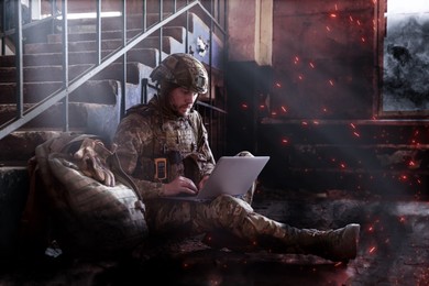 Image of Soldier using laptop inside building during military operation