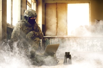 Image of Soldier using laptop inside building during military operation