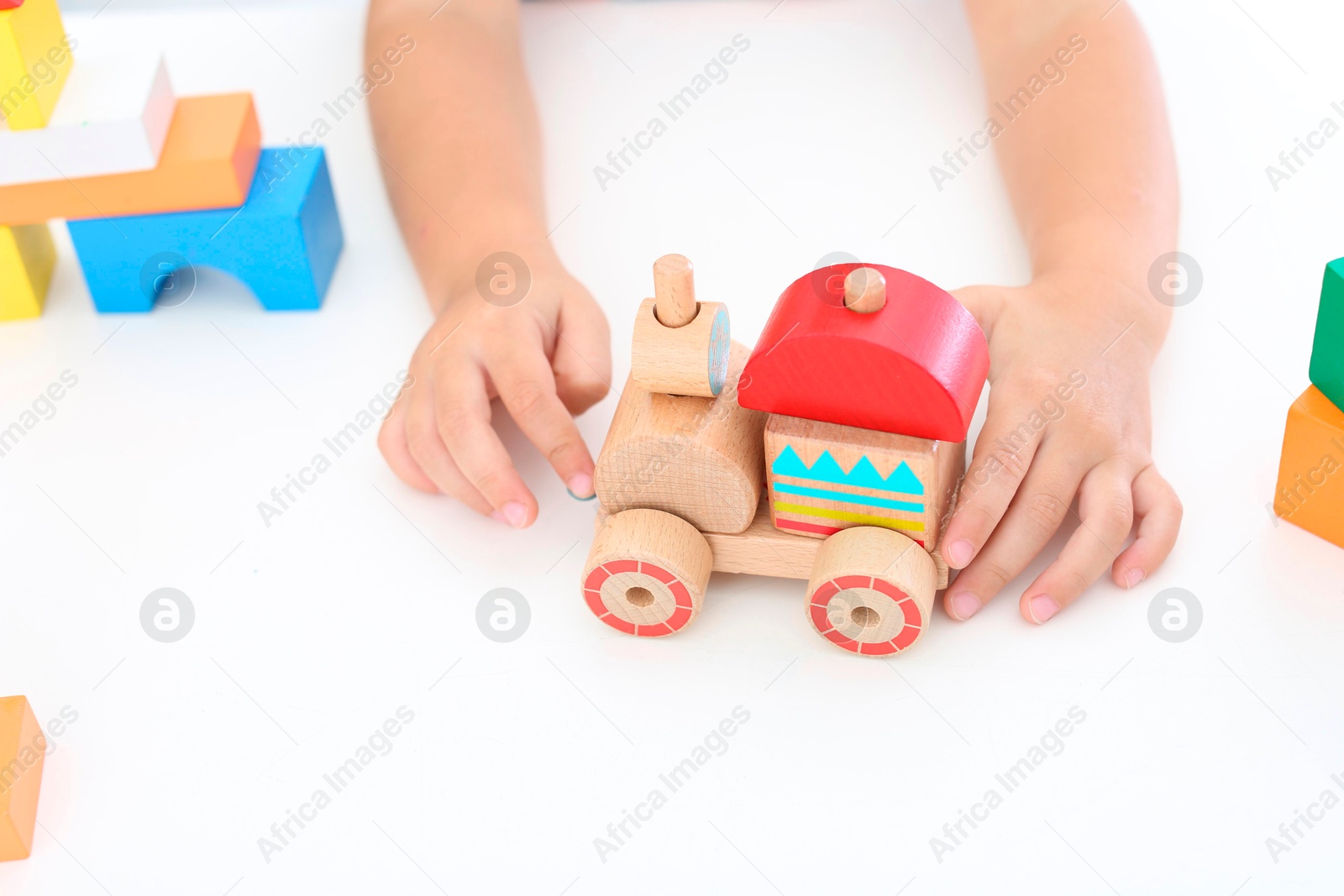 Photo of Little boy playing with toy at white table, closeup