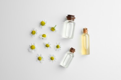 Photo of Aromatherapy. Essential oils and chamomiles on white background, flat lay