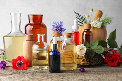 Photo of Aromatherapy. Different essential oils, flowers and green leaves on wooden table