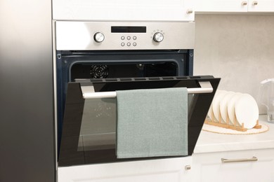 Photo of Open electric oven with towel in kitchen. Cooking appliance