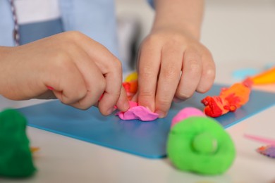 Little boy sculpting with play dough at table indoors, closeup