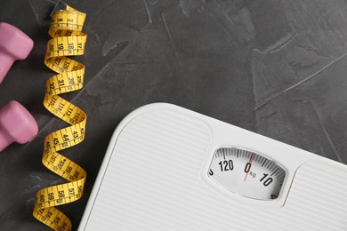 Photo of Bathroom scale, measuring tape and dumbbells on grey textured background, flat lay. Space for text