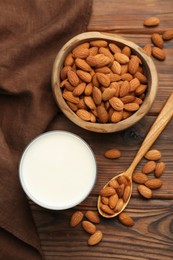 Glass of almond milk and almonds on wooden table, top view