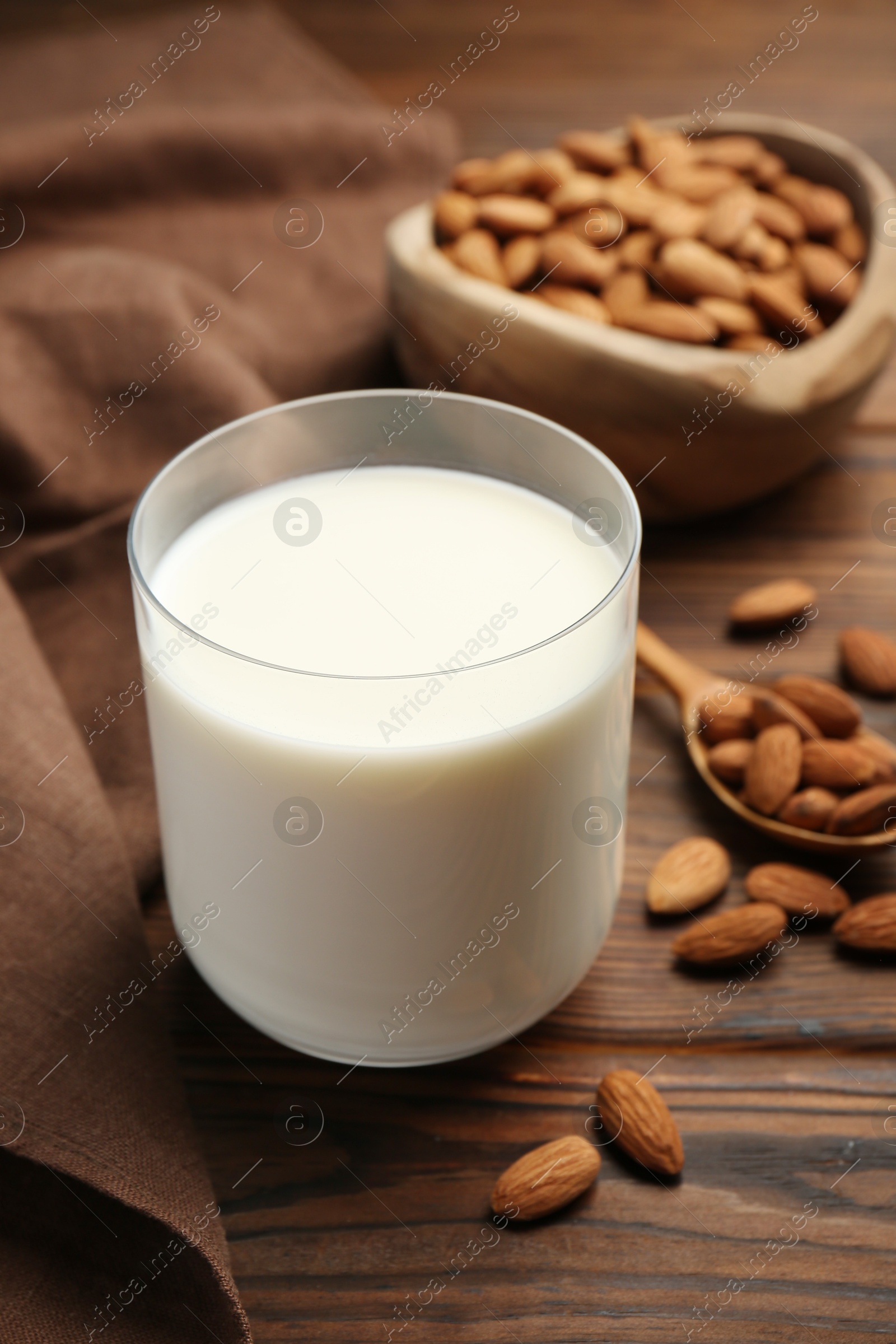 Photo of Glass of almond milk and almonds on wooden table