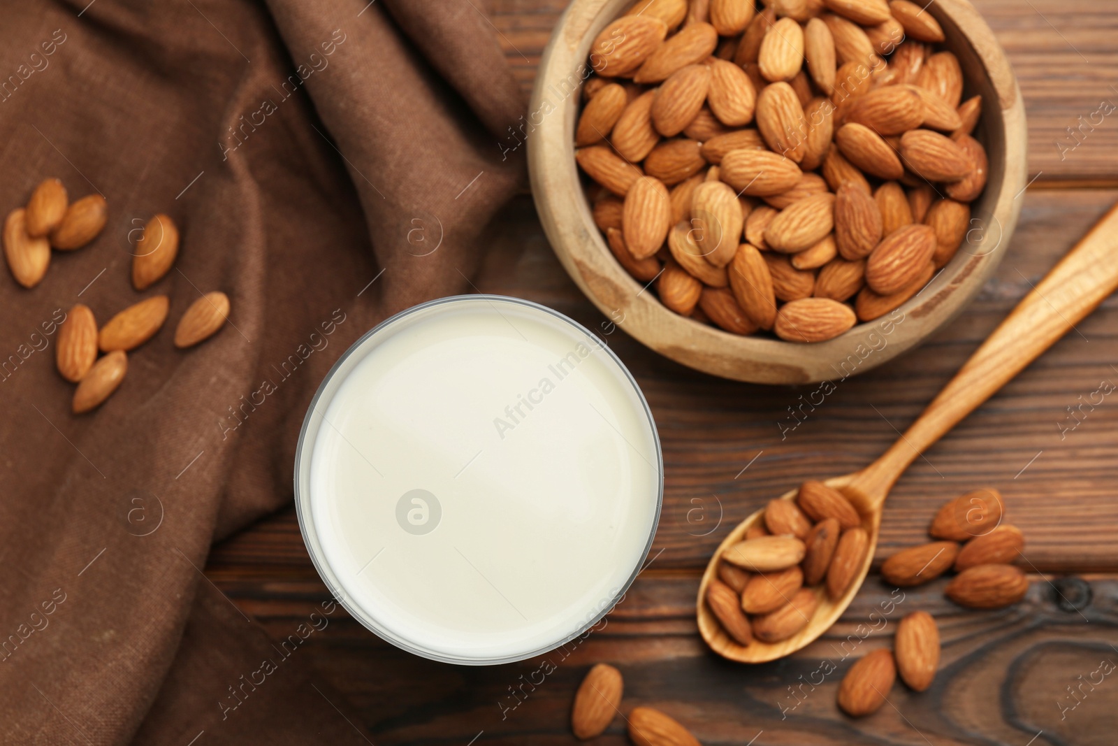 Photo of Glass of almond milk and almonds on wooden table, top view