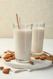 Glasses of almond milk and almonds on white wooden table