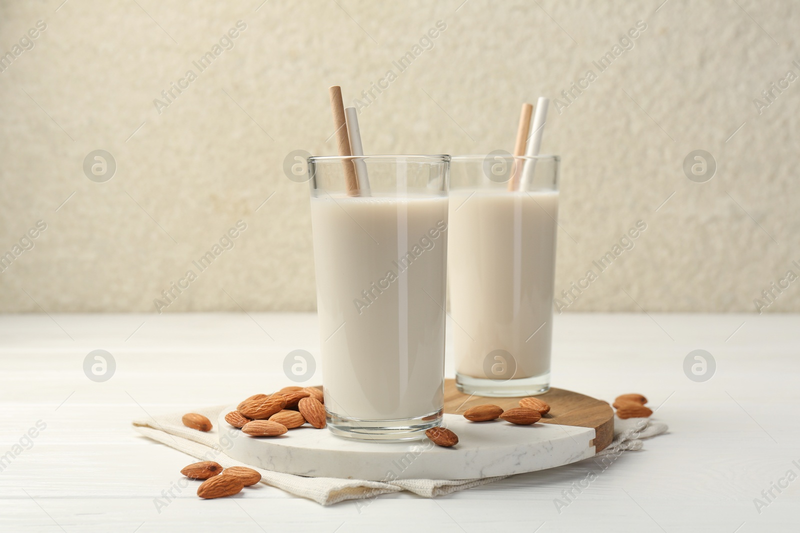 Photo of Glasses of almond milk and almonds on white wooden table