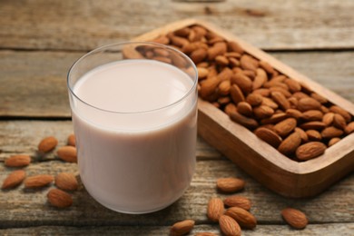 Glass of almond milk and almonds on wooden table