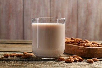 Glass of almond milk and almonds on wooden table