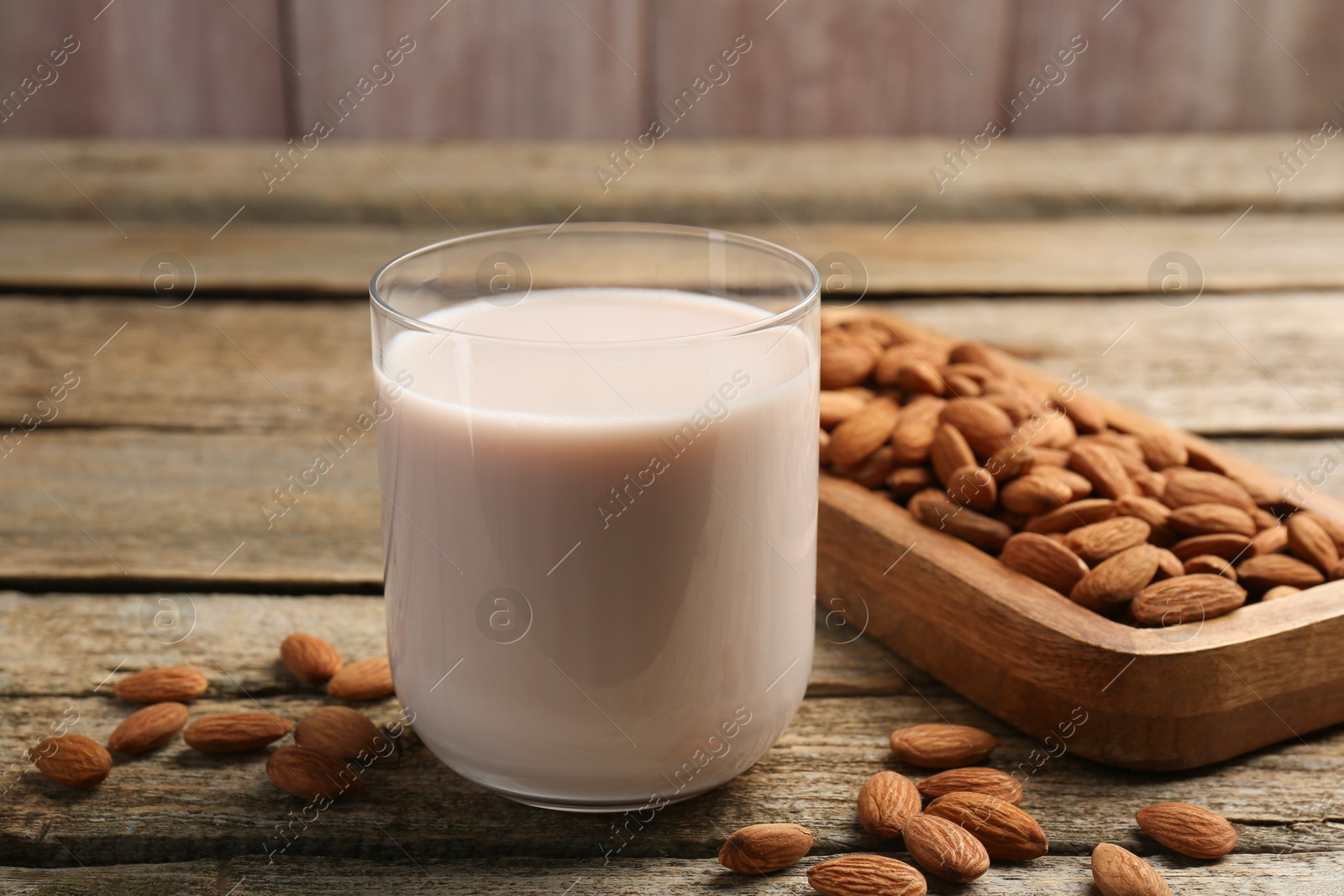 Photo of Glass of almond milk and almonds on wooden table