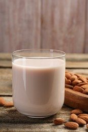 Glass of almond milk and almonds on wooden table