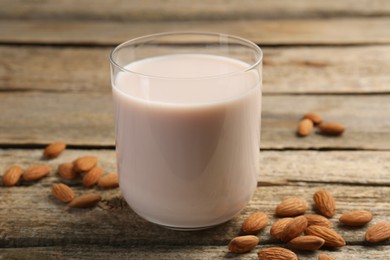 Photo of Glass of almond milk and almonds on wooden table