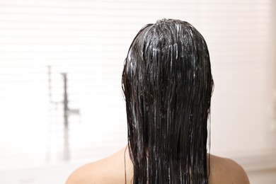 Photo of Woman with applied hair mask in bathroom, back view. Space for text