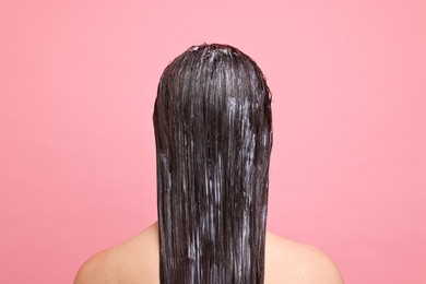 Photo of Woman with applied hair mask on pink background, back view