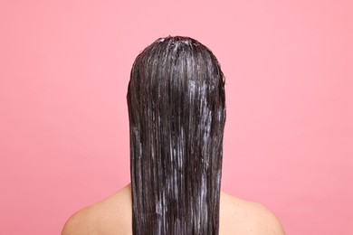 Woman with applied hair mask on pink background, back view