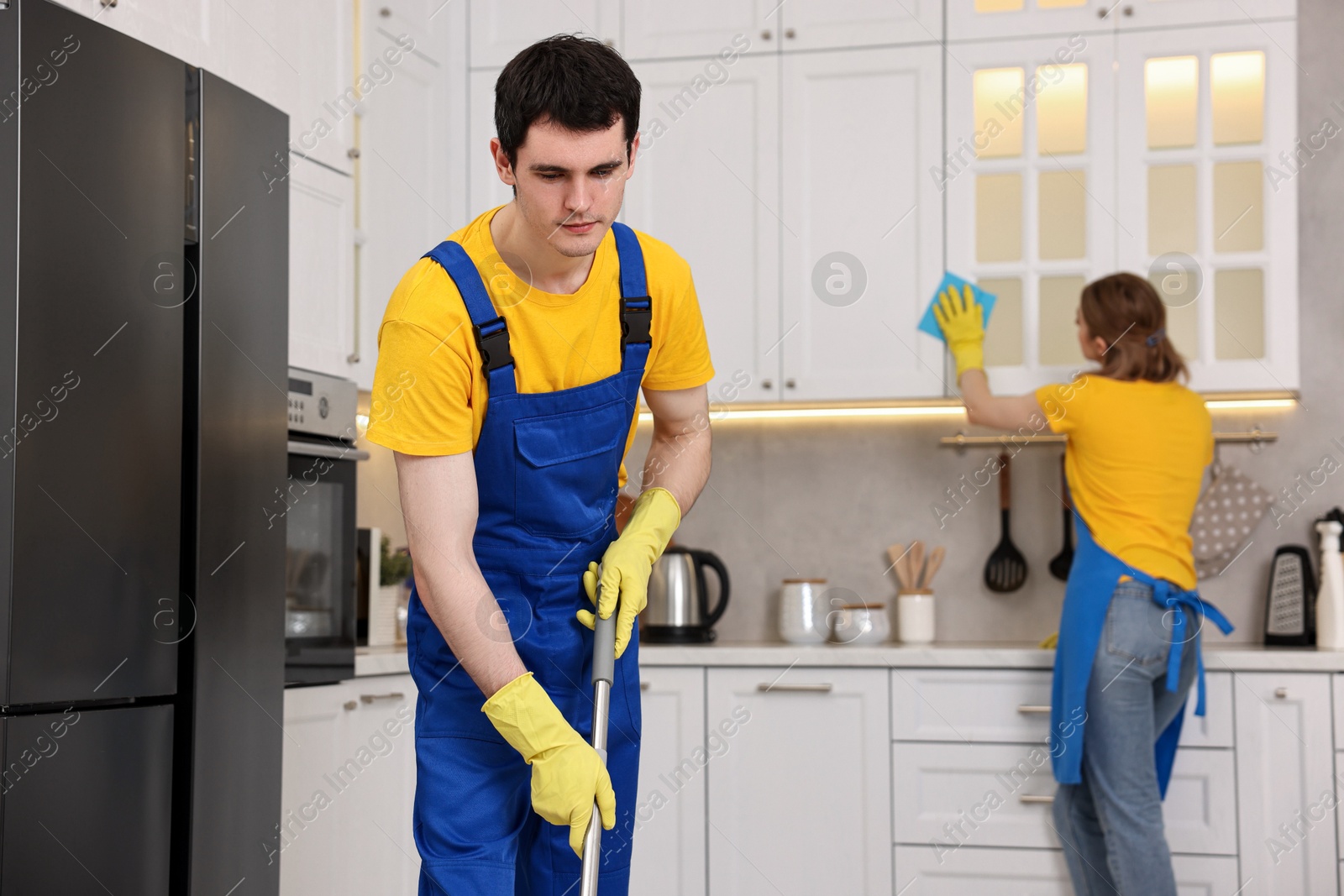 Photo of Professional janitors working in kitchen. Cleaning service