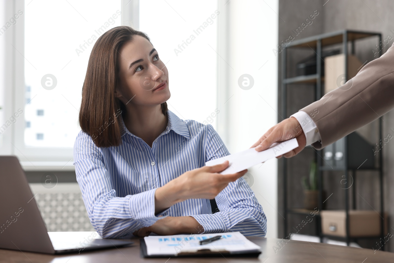 Photo of Boss giving salary in paper envelope to employee indoors