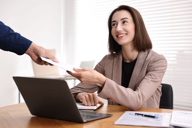 Photo of Boss giving salary in paper envelope to employee indoors