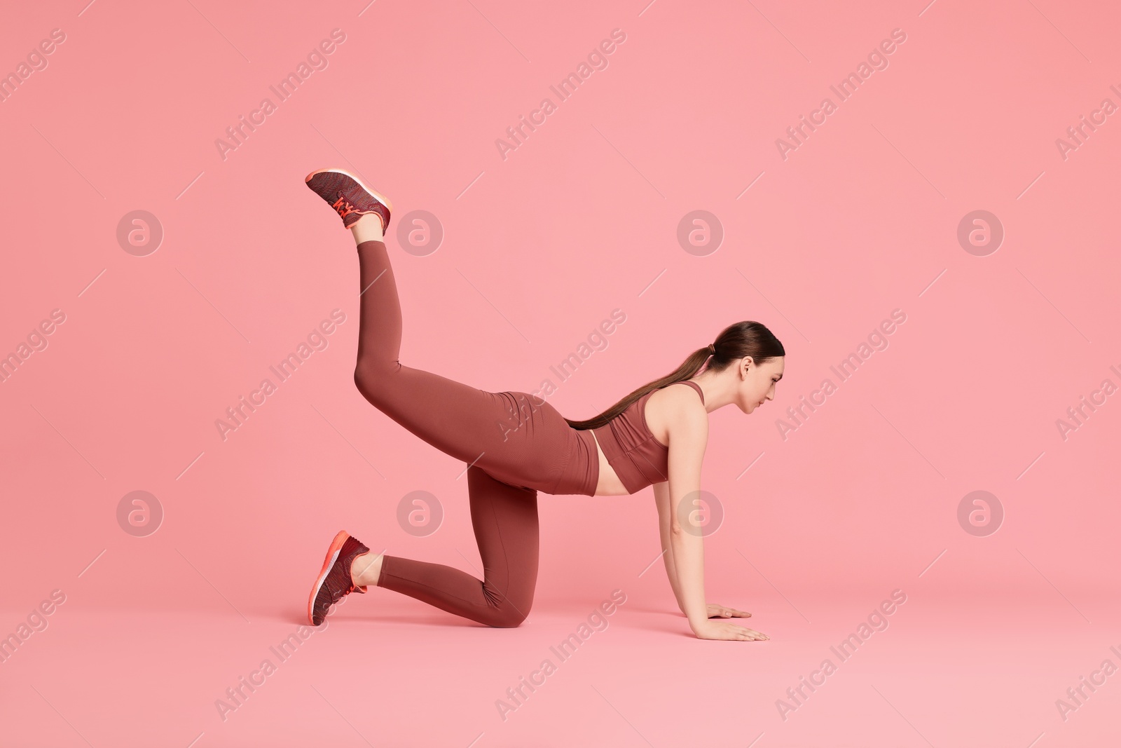 Photo of Young woman doing aerobic exercise on pink background