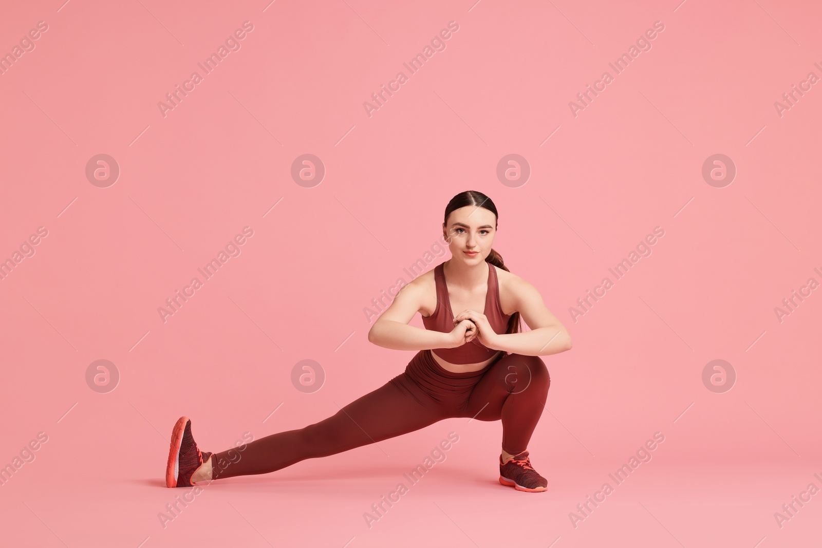 Photo of Aerobics. Young woman doing stretching exercise on pink background