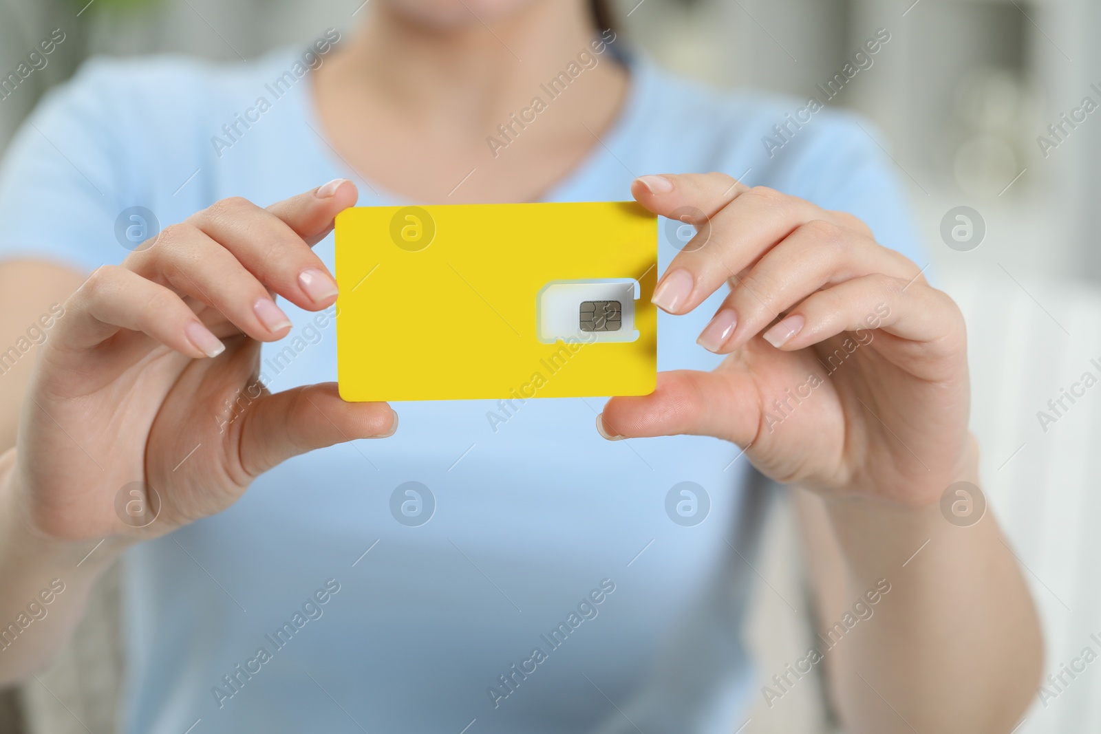 Photo of Woman holding SIM card at home, closeup