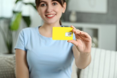Photo of Woman holding SIM card at home, selective focus