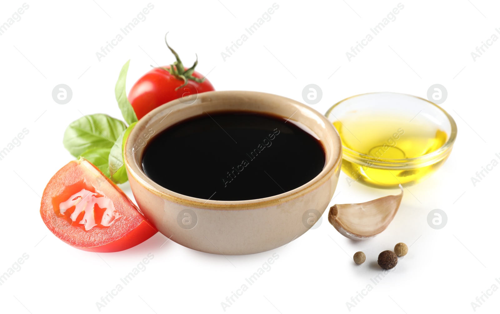 Photo of Balsamic vinegar in bowl, oil, tomatoes, basil and spices isolated on white