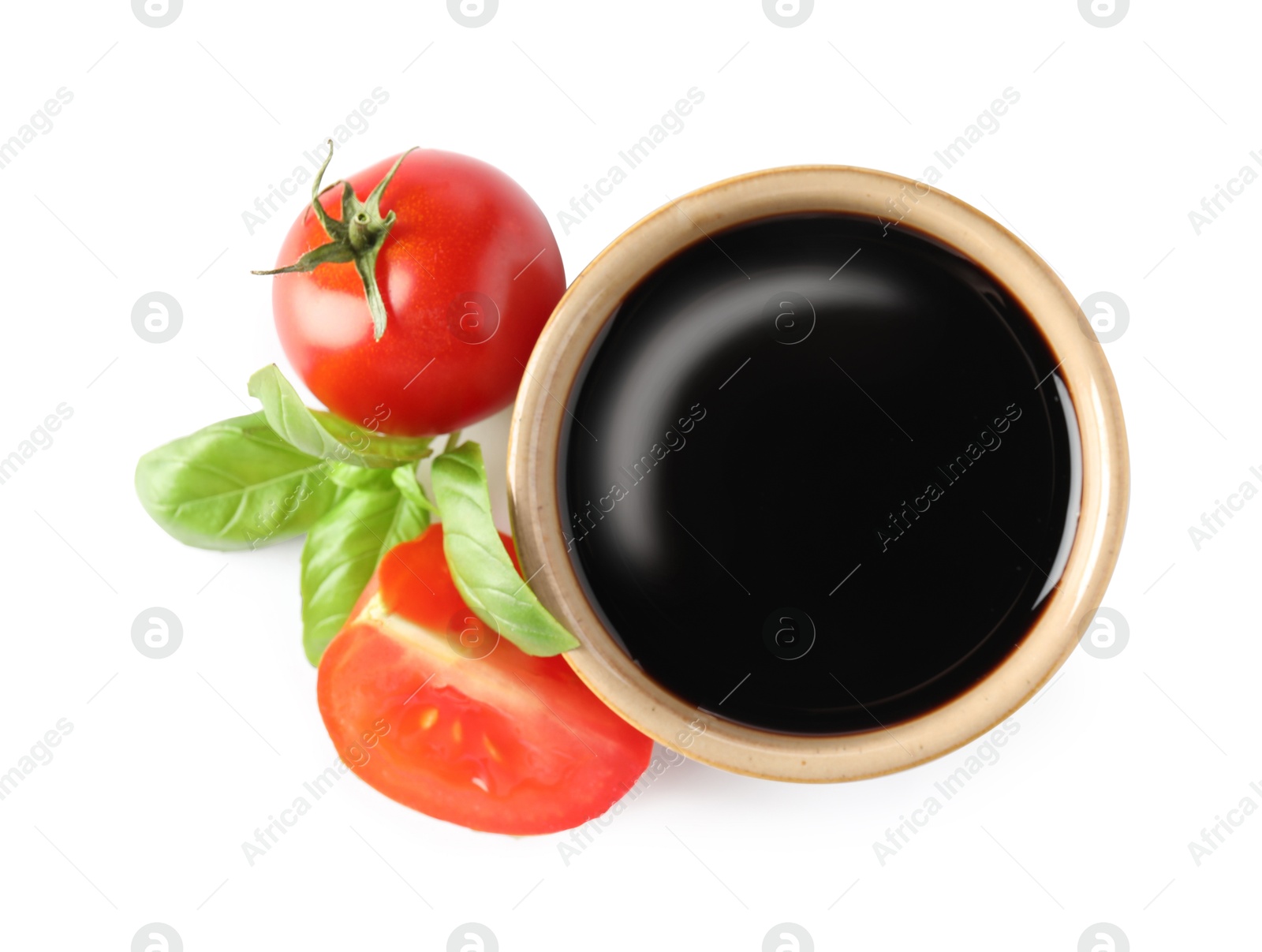 Photo of Balsamic vinegar in bowl, tomatoes and basil isolated on white, top view