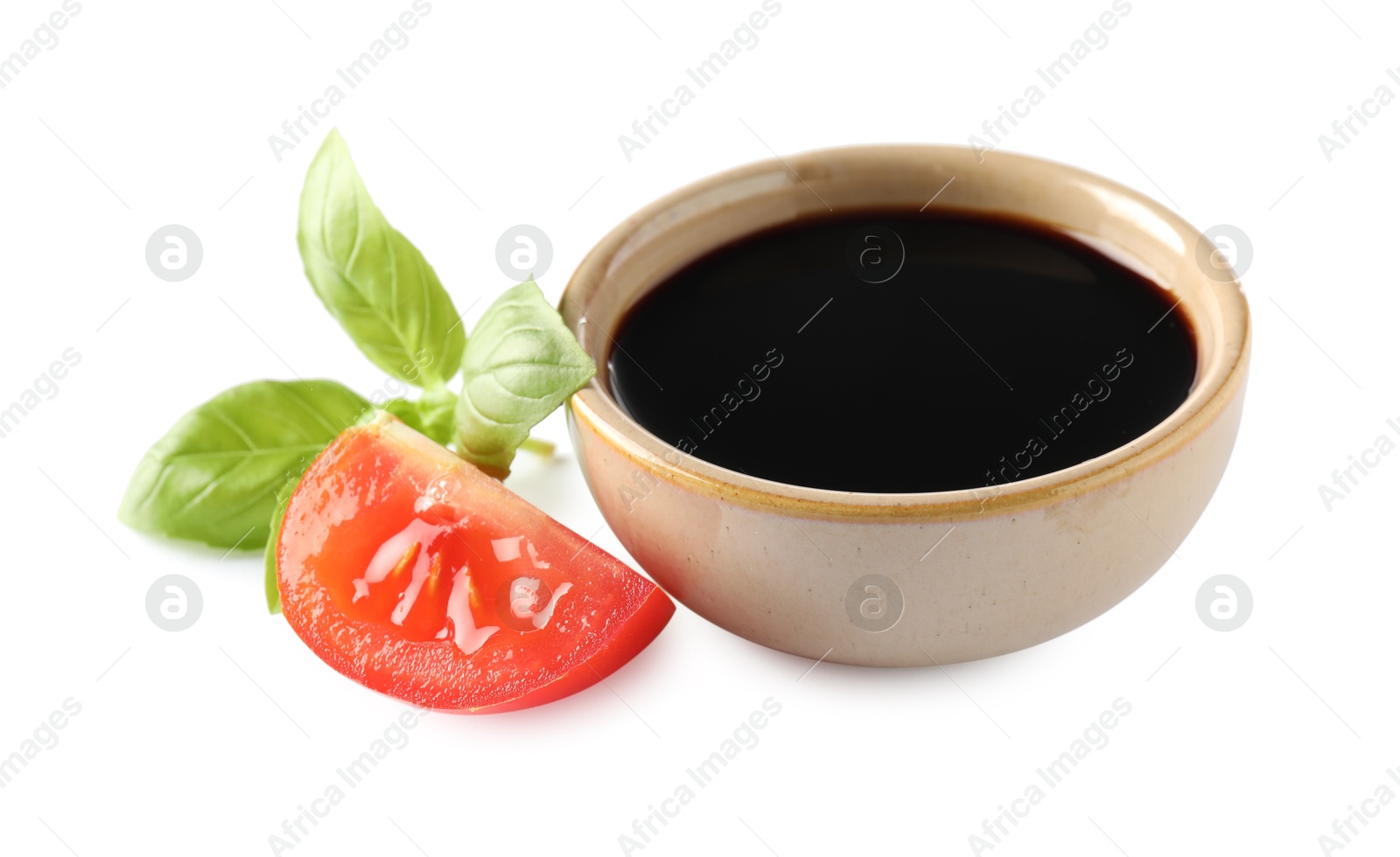 Photo of Balsamic vinegar in bowl, tomato and basil isolated on white