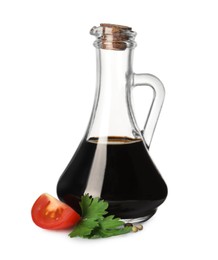 Photo of Balsamic vinegar in glass jug, parsley and tomato isolated on white