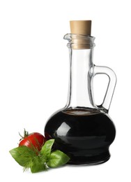 Balsamic vinegar in glass jug, herbs and tomato isolated on white