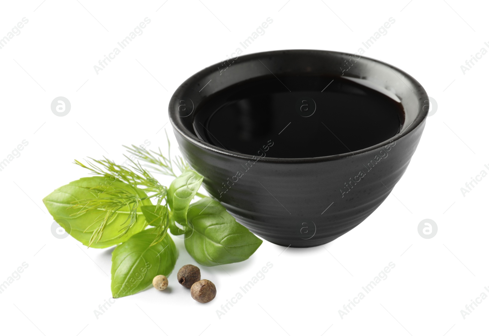 Photo of Balsamic vinegar in bowl, herbs and spices isolated on white