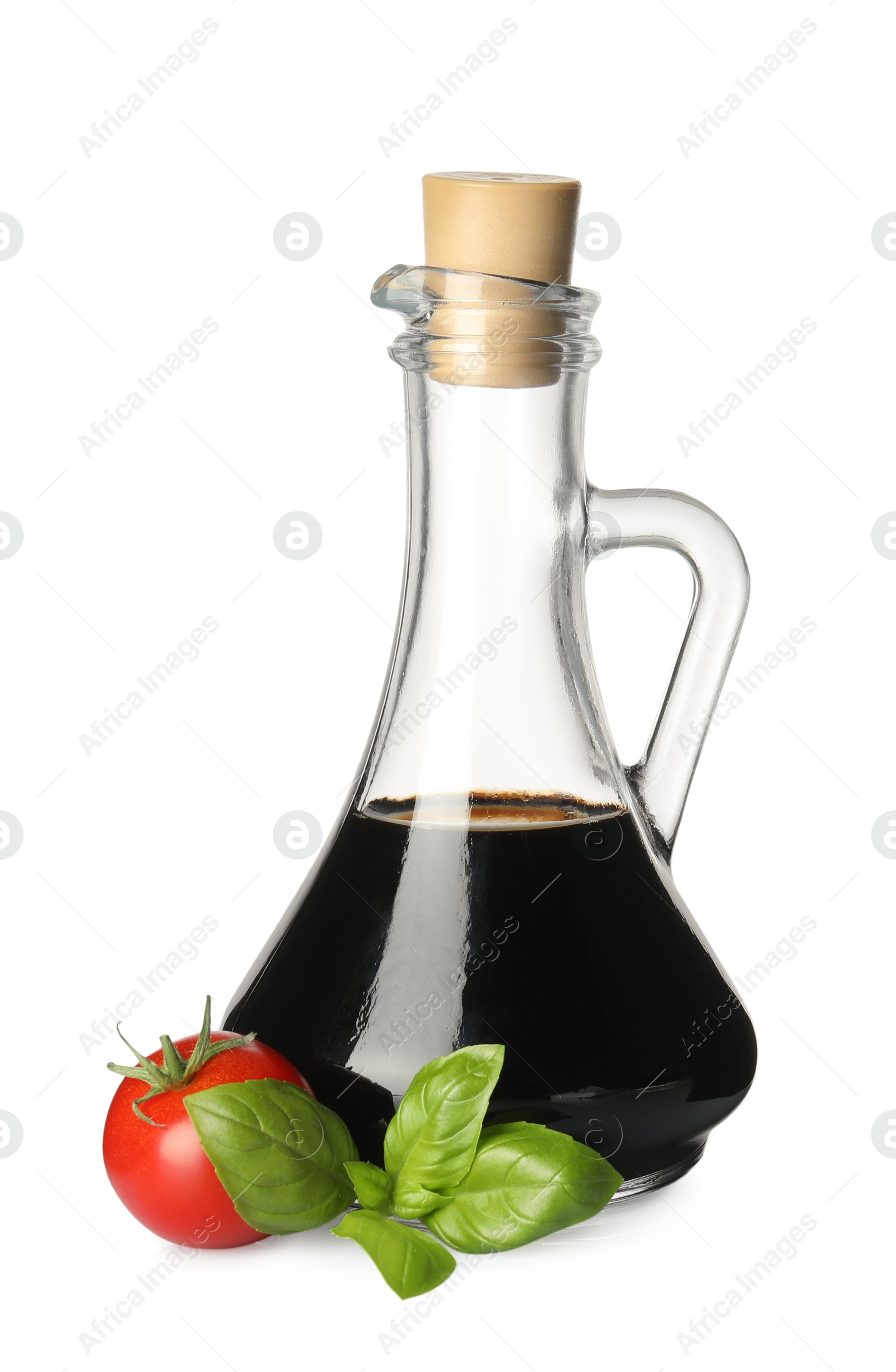 Photo of Balsamic vinegar in glass jug, tomato and basil isolated on white