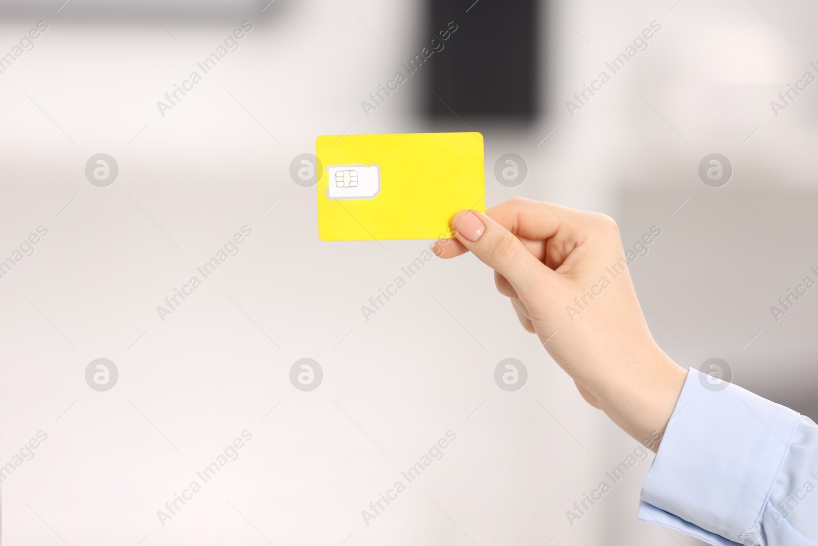 Photo of Woman holding modern SIM card indoors, closeup