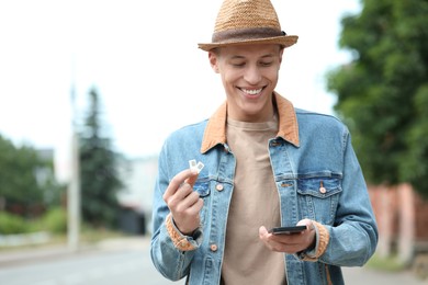 Photo of Happy man with SIM cards and smartphone outdoors, space for text